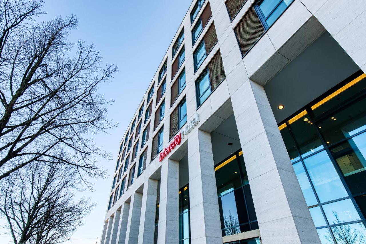 Intercityhotel Berlin Airport Ber Terminal 1 & 2 Schönefeld Exteriér fotografie The photo shows a modern building with a sleek, contemporary design. The structure features several large windows and a façade composed of light-colored stone. There is a visible entrance with glass doors, and the building appears to be several stori